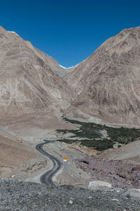 Scenic view of mountain road against clear blue sky