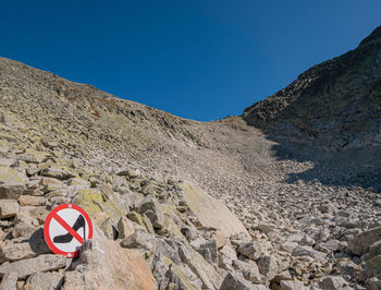 Road sign on rocks against clear blue sky