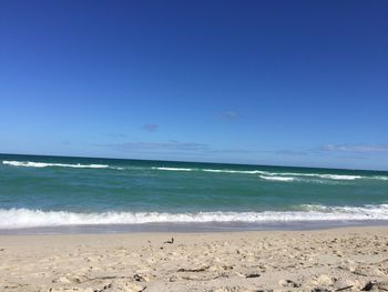 Scenic view of beach against clear blue sky