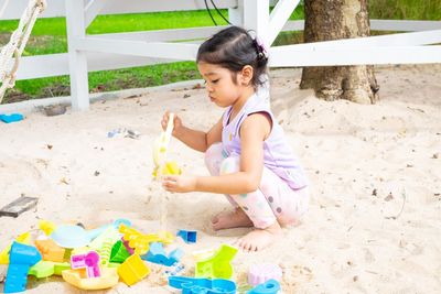 Cute girl playing with toy sitting on land