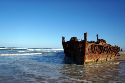 Abandoned boat in sea against clear sky