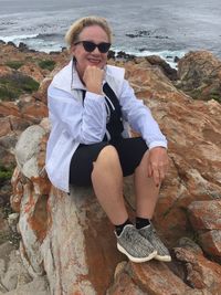 Portrait of woman sitting on rock at beach