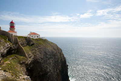 Lighthouse by sea against sky