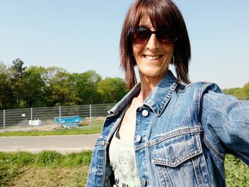 Smiling woman standing by road on field