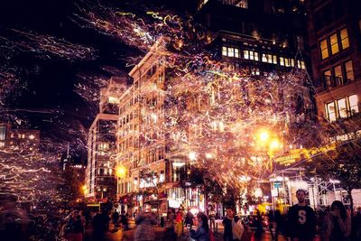 Crowd on illuminated street amidst buildings in city at night