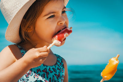 Cute girl looking away while eating ice cream at beach