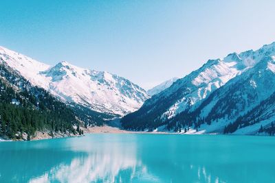 Scenic view of lake and mountains against clear blue sky