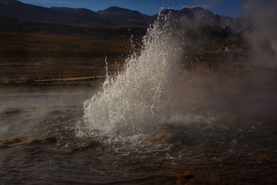 Water splashing on mountain against sky