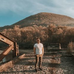 Portrait of young man standing on mountain against sky