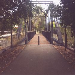 Footbridge amidst trees against sky