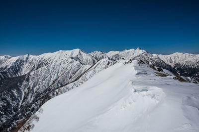 Scenic view of snowcapped mountains against clear blue sky