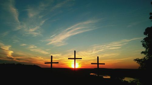 Silhouette cross against sky during sunset