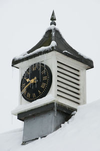 Low angle view of clock on snow covered structure