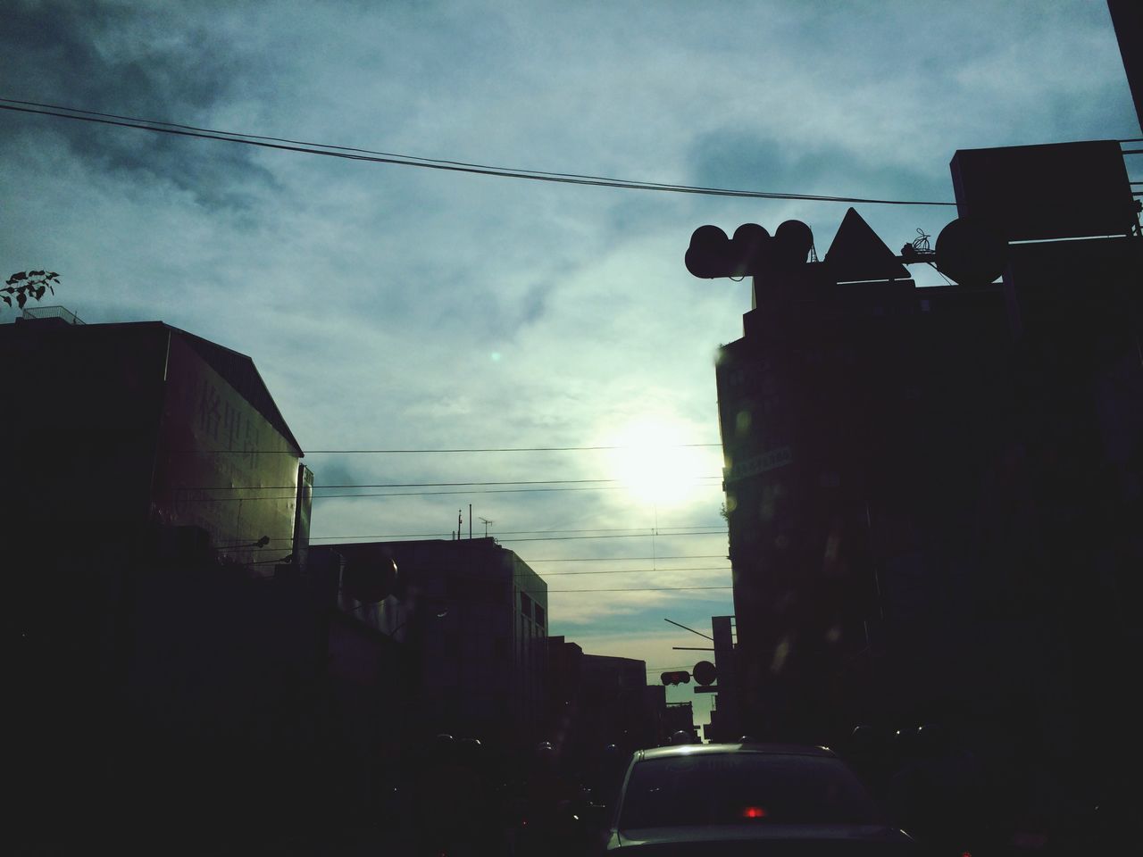 sky, low angle view, building exterior, built structure, architecture, silhouette, cloud - sky, sunlight, sunbeam, cloud, outdoors, house, sun, sunset, street light, building, men, lens flare