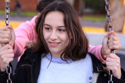 Portrait of smiling woman on swing in playground