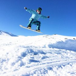 Low angle view of man snowboarding against clear blue sky