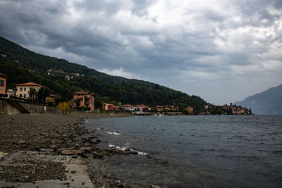 Houses by sea against sky