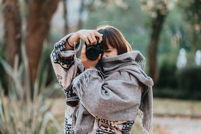 Woman photographing in forest