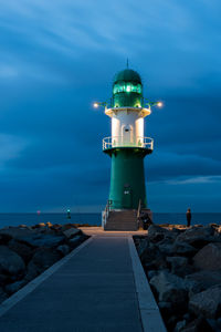 Lighthouse by sea against sky at night