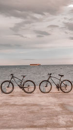 Bicycles by sea against sky