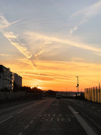 Cars on road against sky during sunset