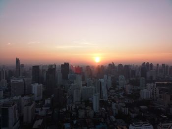 Aerial view of buildings in city against sky during sunset