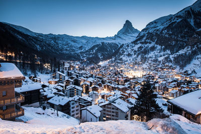 Snow covered houses and mountains against sky