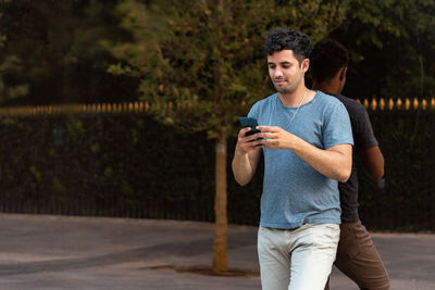 Man looking at camera while standing on mobile phone