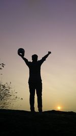 Silhouette man standing on field against clear sky during sunset