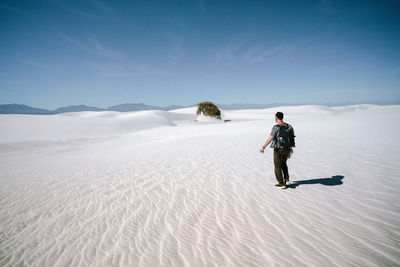 Full length of man walking on sand against sky