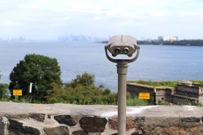 Close-up of coin-operated binoculars by retaining wall