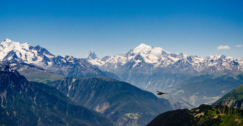 Scenic view of snowcapped mountains against blue sky