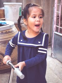 Cute girl shouting while standing with push scooter