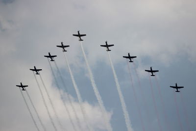 Low angle view of airshow against cloudy sky