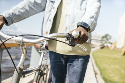 Young man pushing bicycle by the sea