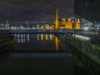 Illuminated buildings by river at night