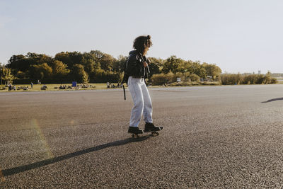 Young woman skating in park on sunny day