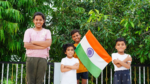 Little kids showing indian flag and looking at camera while standing on terrace. child celebrating i