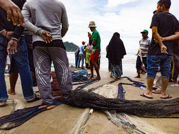 Rear view of people standing on shore against sky