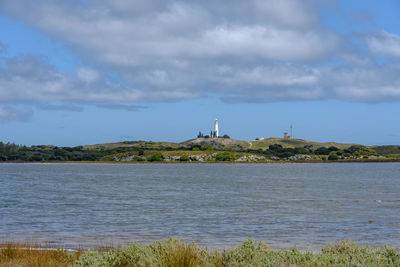 Lighthouse by sea against sky