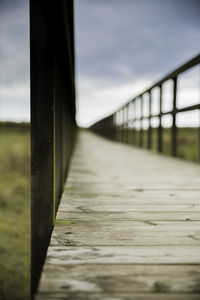 Surface level of wooden bridge against sky