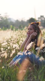 Thoughtful young woman sitting amidst plants on field