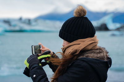 Rear view of man photographing on sea during winter