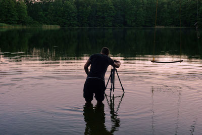 Rear view of man on lake against trees