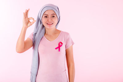 Portrait of woman standing against pink background