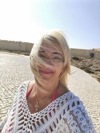 Portrait of smiling woman on footpath against clear sky