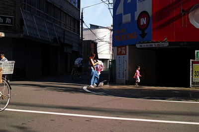 People walking on street against buildings in city