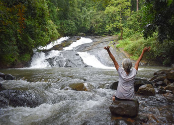 Rear view of man jumping in waterfall