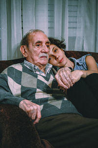 Portrait of woman with father sitting on sofa at home