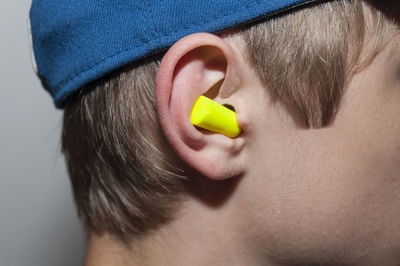 Close-up of boy with yellow chalk in ear